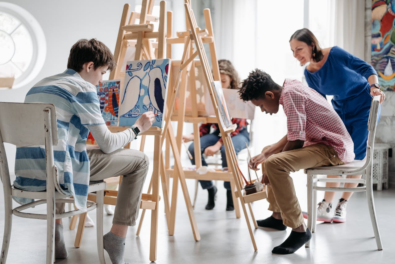 Children painting in a classroom with teacher guidance, focusing on creativity and learning.